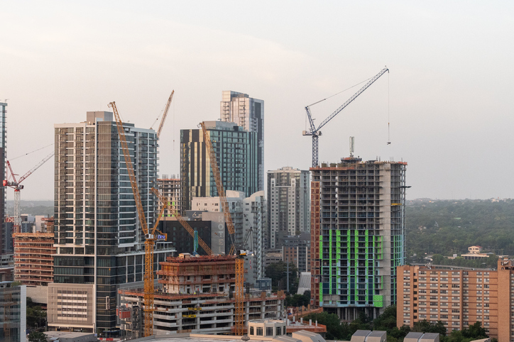 Aerial view of a growing mid-size city skyline with cranes, reflecting rising investment in secondary commercial real estate markets