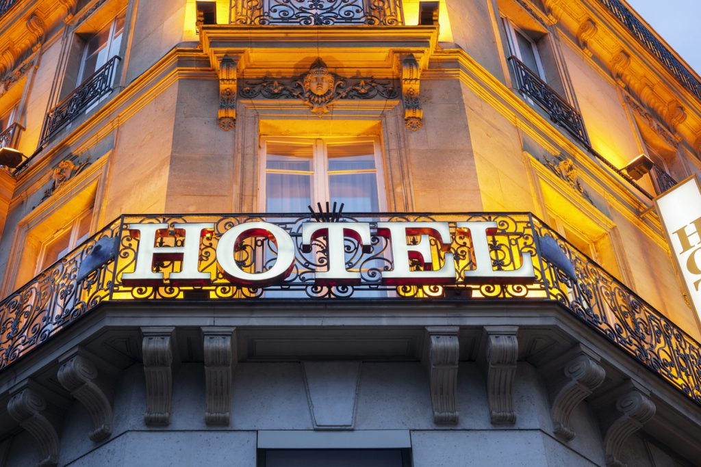 Illuminated hotel sign on an ornate iron balcony, the type of asset commercial real estate companies known for hospitality evaluate