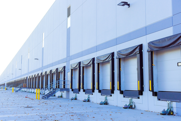 Modern industrial warehouse with a row of loading docks, the kind of single-tenant NNN investment properties drawing capital in 2026.